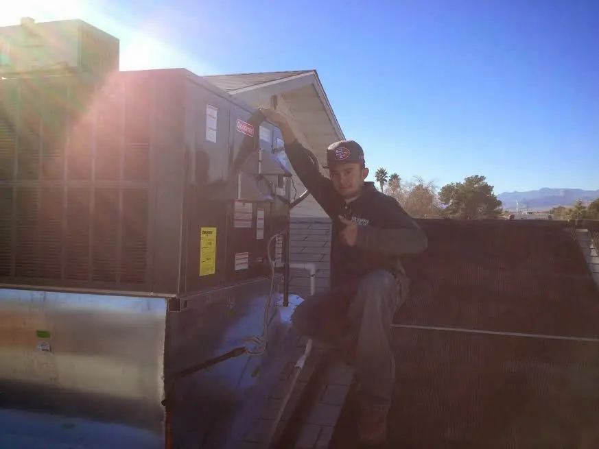 HVAC technician performing Air Duct Repair on a rooftop unit in Waseca